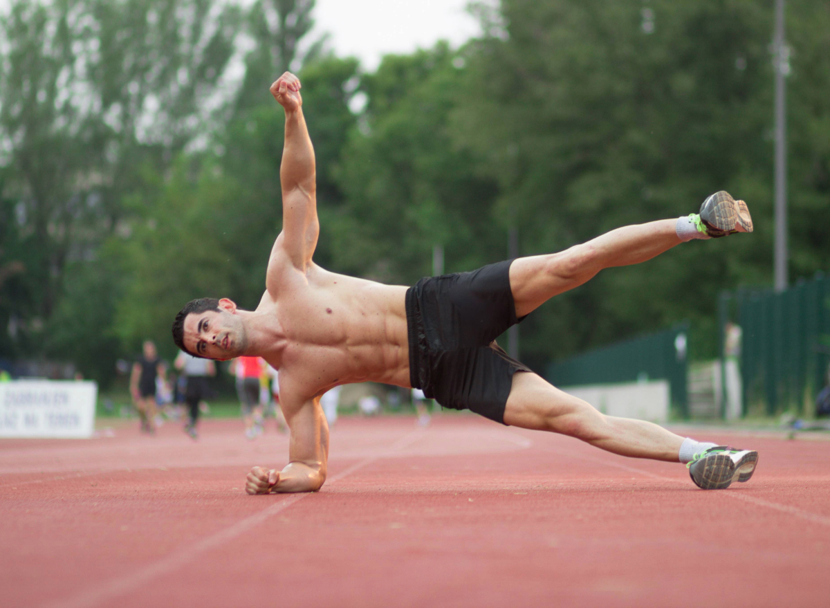 fit, muscular man doing side plank with leg raise, concept of floor workouts to improve muscular endurance