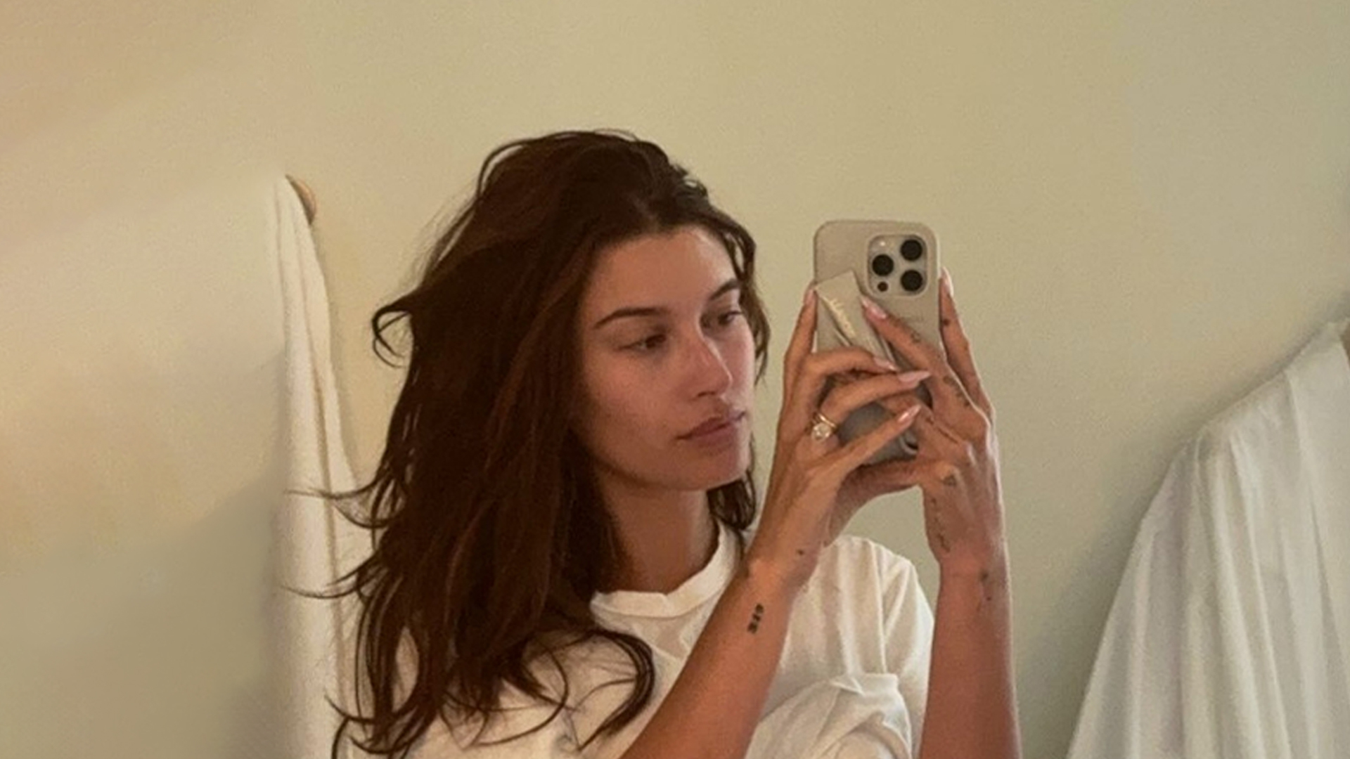 Hailey Bieber lifts her shirt to show off toned abs after being accused of ‘trying to look single’ on vacation