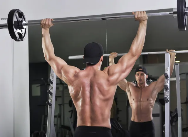 man overhead barbell press, concept of workout for men to build boulder shoulders