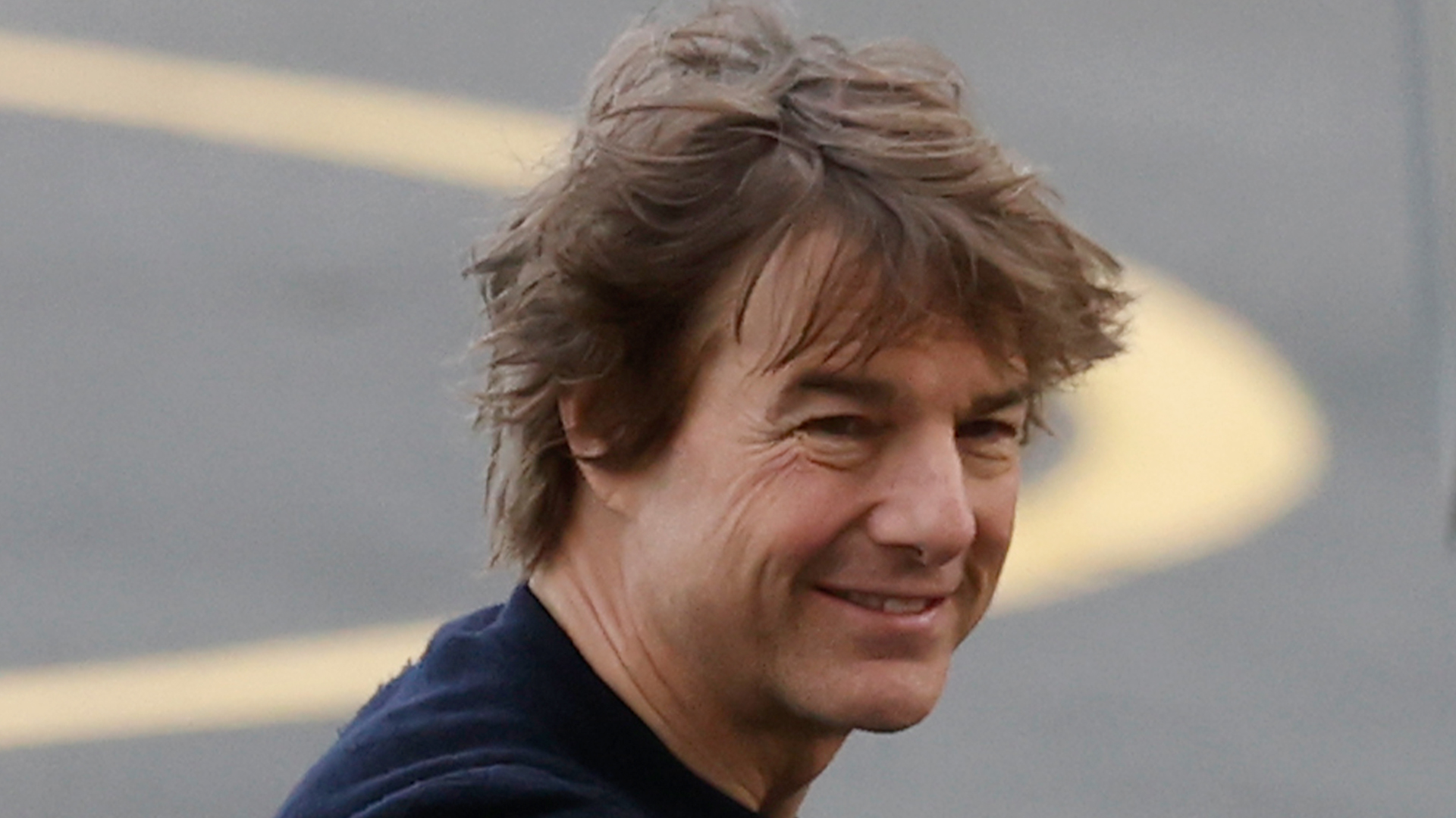 Tom Cruise spotted sporting his Mop Gun hairdo and flashes big grin for the cameras while arriving at heliport in London