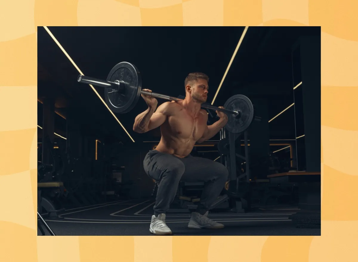 fit, muscular man doing barbell back squats in dark gym