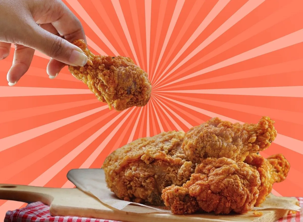 Woman holding a drumstick over a plate of hot fried chicken against a colorful background