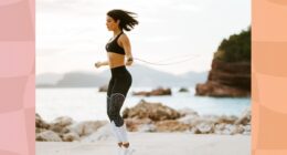 fit brunette woman in black sports bra and black and white leggings doing jump rope workout at the beach