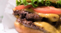 A closeup of the double cheeseburger with tomato lettuce and onion, from Shake Shack.