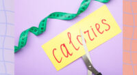 cutting calories concept of scissors cutting a piece of paper with the word calories