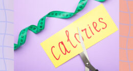 cutting calories concept of scissors cutting a piece of paper with the word calories