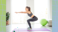 focused brunette woman doing squats exercise on yoga mat in bright living room at home