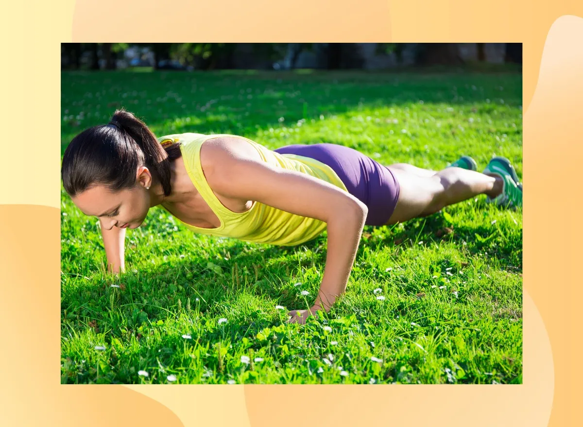 brunette woman in yellow tank and purple shorts doing pushups in bright grassy lawn