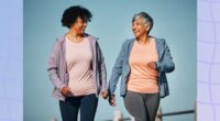 mature female friends walking for exercise outdoors and talking