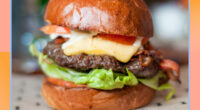 bacon cheeseburger with lettuce and tomato on a designed background