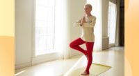 woman doing tress pose in yoga room