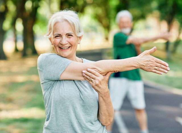 happy senior woman stretching outdoors