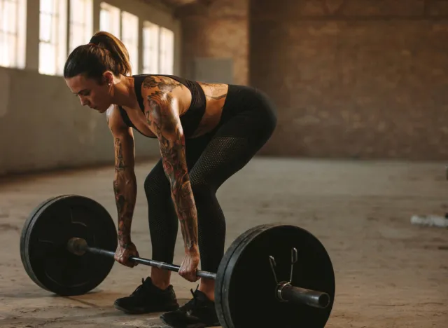 fit, muscular woman doing barbell deadlift exercise