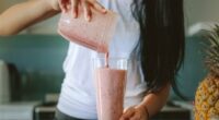 woman pouring smoothie into glass