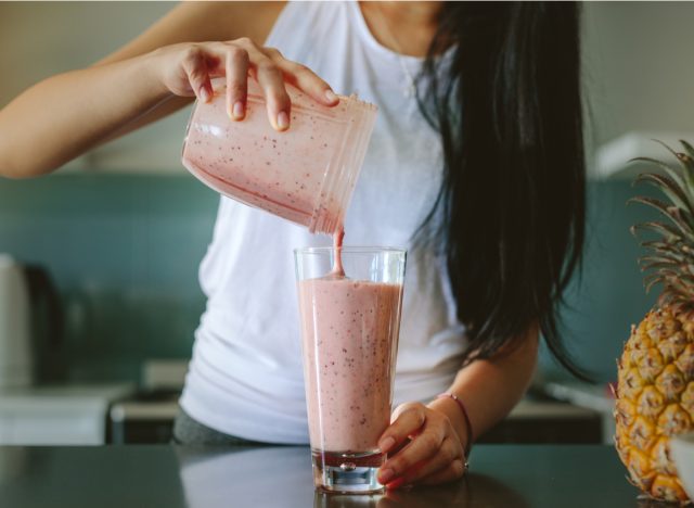 woman pouring smoothie into glass