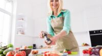 happy woman making salad in bright kitchen with fresh vegetables on countertop