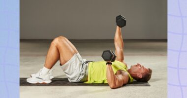 fit, muscular man in lime green tank top and gym shorts doing dumbbell chest press on the floor