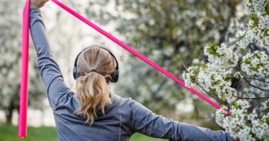 woman doing resistance band exercise outdoors, concept of resistance band workouts to stay active and fit as you age