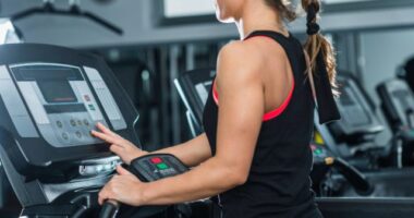 woman adjusting the treadmill incline at the gym