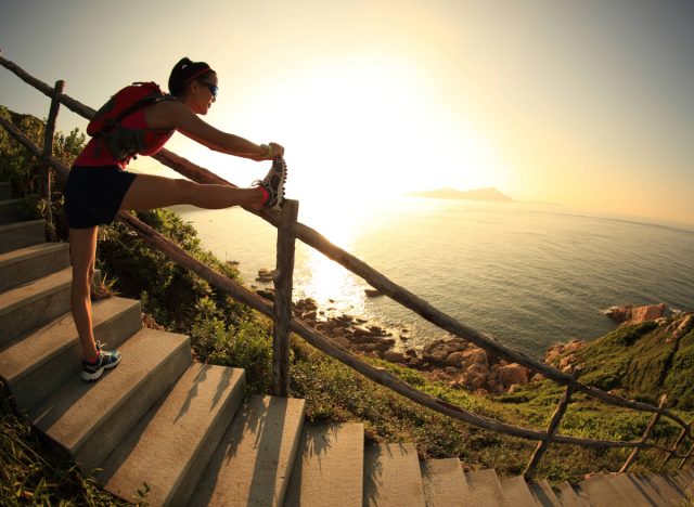 woman with rucksack stretching outdoors on stair trail