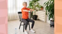 fit, mature woman doing seated ab exercise at home with dumbbells in bright living room