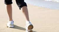 close-up of woman's sneakers, walking on the sand on the beach