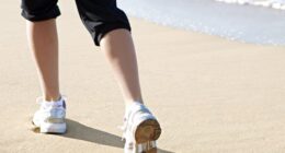 close-up of woman's sneakers, walking on the sand on the beach