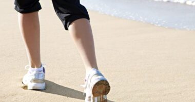 close-up of woman's sneakers, walking on the sand on the beach