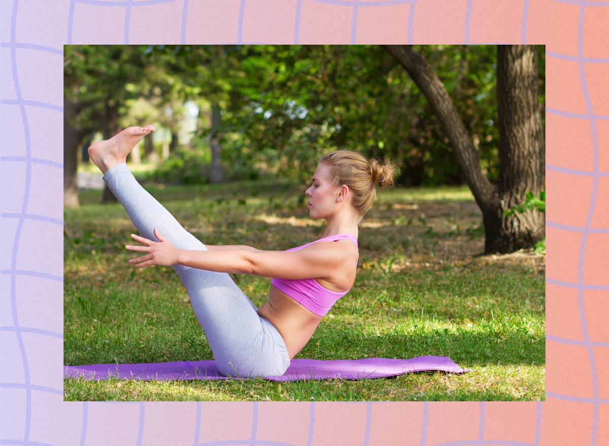 fit woman doing boat pose on yoga mat in grassy lawn