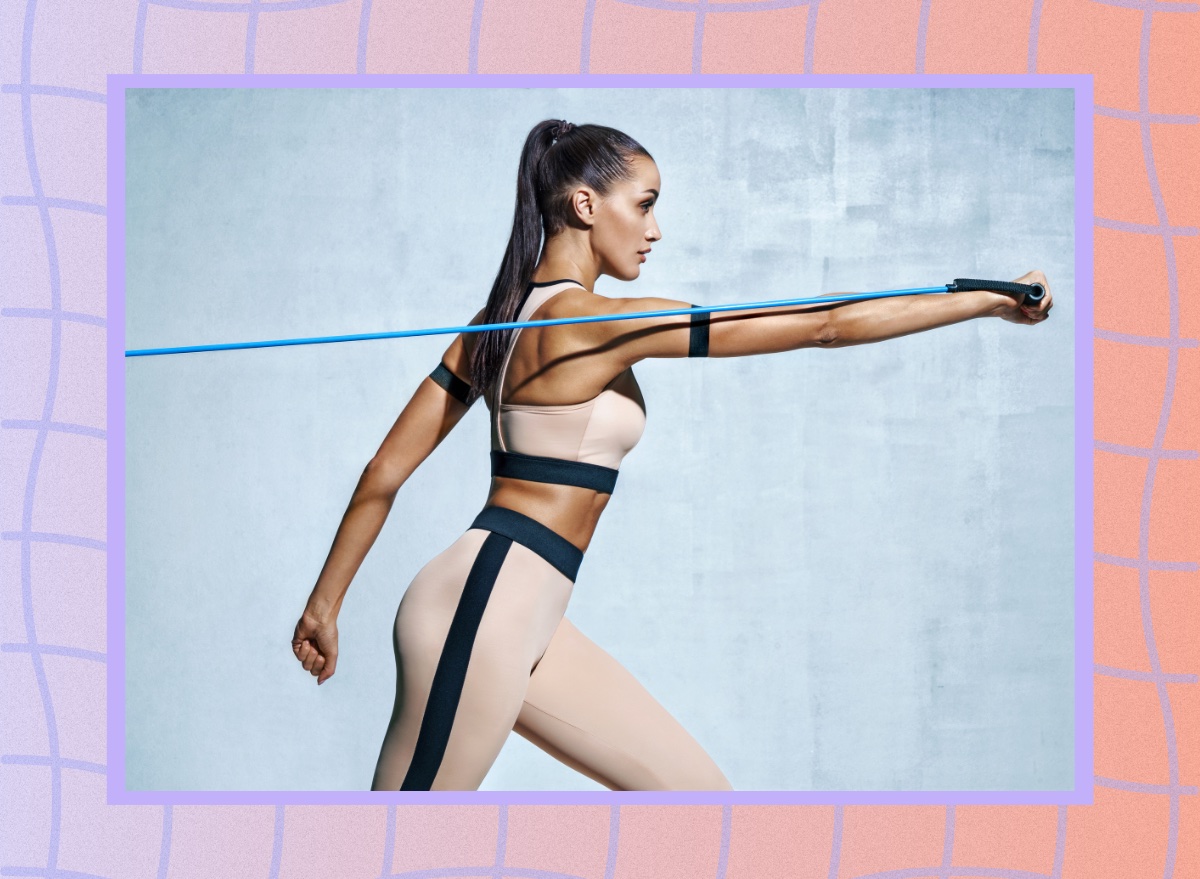 fit woman performing resistance band exercise for her abs in front of grey backdrop