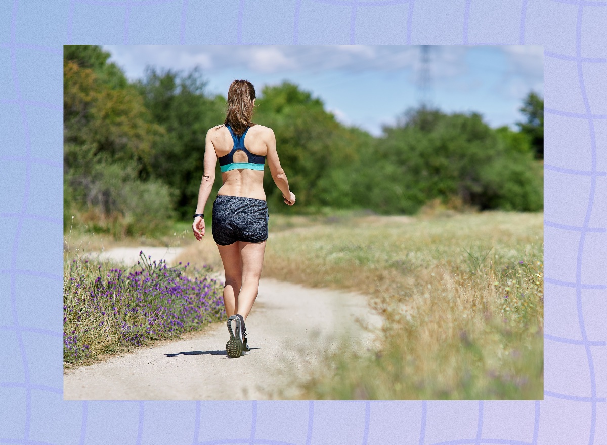 woman going on trail walk surrounded by grass and wildflowers on sunny day