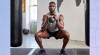 muscular man doing kettlebell squat at the gym