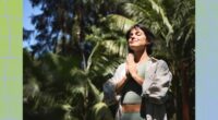 fit brunette woman meditating outdoors in the sunlight among lush green vegetation