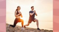 fit couple doing walking lunges on the beach at sunset