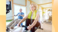 mature couple using rowing machines in bright gym