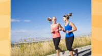 two fit female friends running outdoors on a scenic trail on sunny day