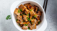 bowl of air fryer teriyaki tofu topped with scallions and sesame seeds