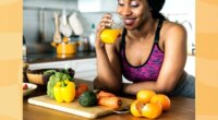 happy woman drinking homemade orange juice in her kitchen