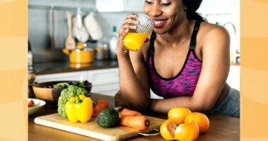 happy woman drinking homemade orange juice in her kitchen