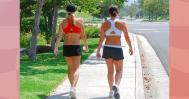 female friends walking outdoors on sidewalk for exercise on sunny day