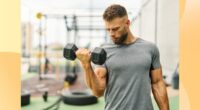 fit, muscular man lifting a dumbbell at outdoor gym