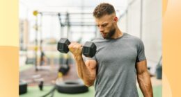 fit, muscular man lifting a dumbbell at outdoor gym