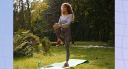 focused woman doing single-leg balance exercise on yoga mat in field on sunny day