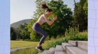 fit woman doing jump squat exercise on stairs outdoors