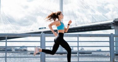 woman running by water in city, concept of workout habits to lose 10 pounds in a month