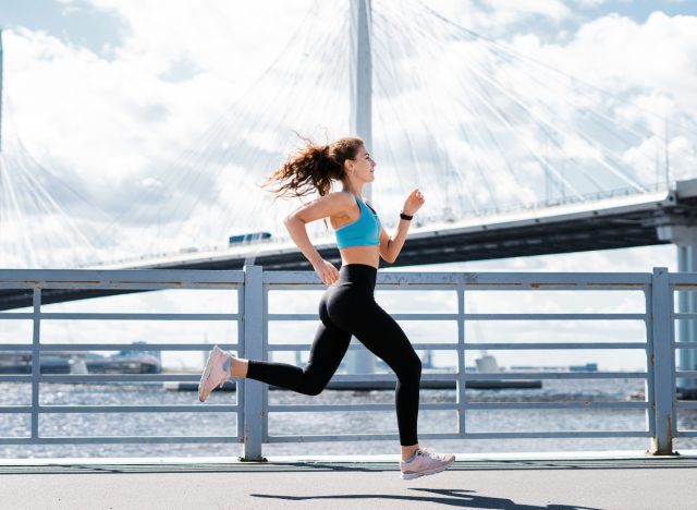 woman running by water in city, concept of workout habits to lose 10 pounds in a month