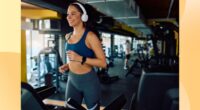 happy brunette woman running on the treadmill at the gym