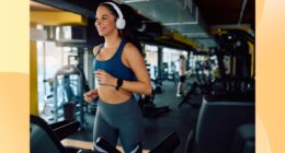 happy brunette woman running on the treadmill at the gym