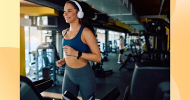 happy brunette woman running on the treadmill at the gym