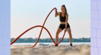 fit woman working out with battle ropes on the beach